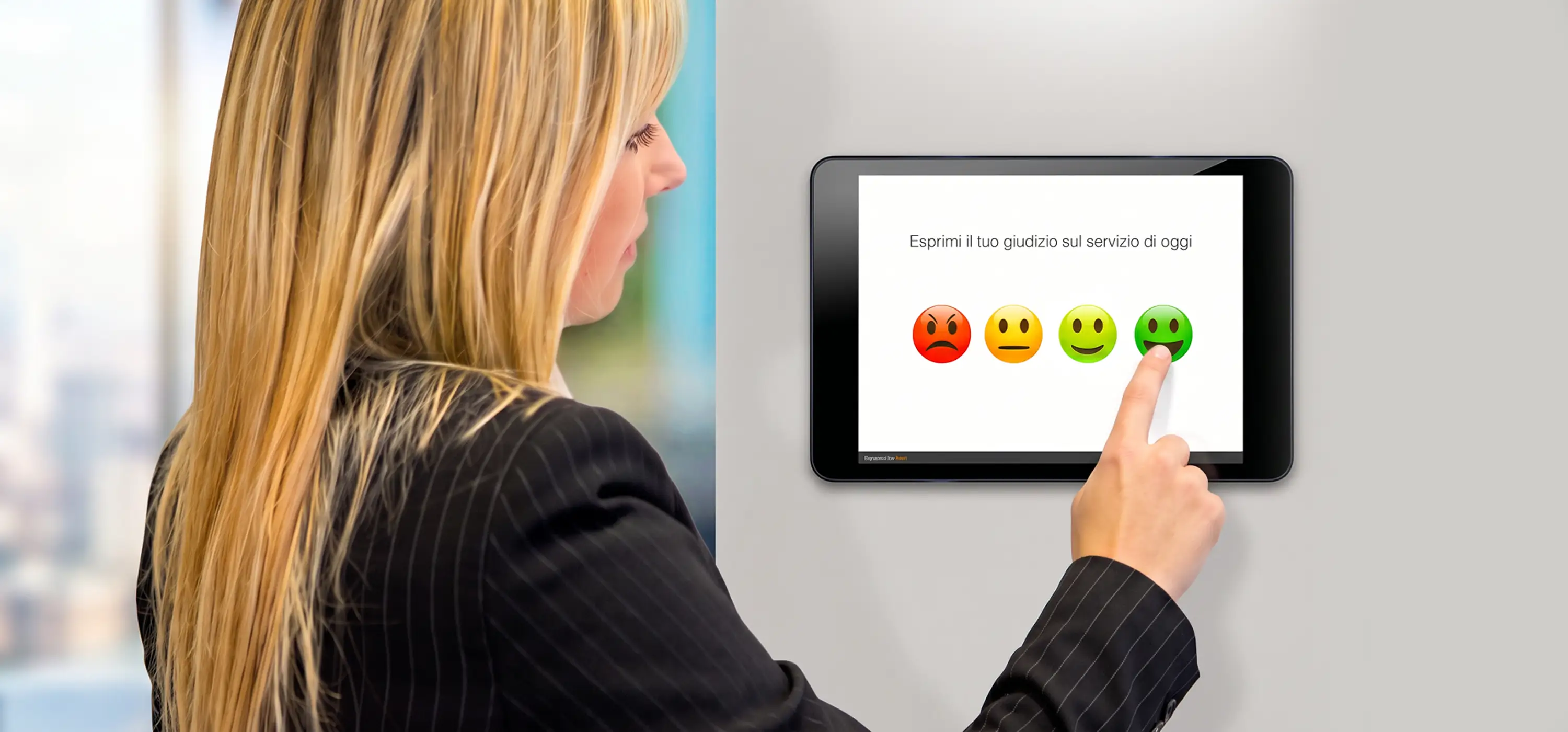 ragazza che risponde ad un sondaggio emoticon o instant survey con tablet a muro