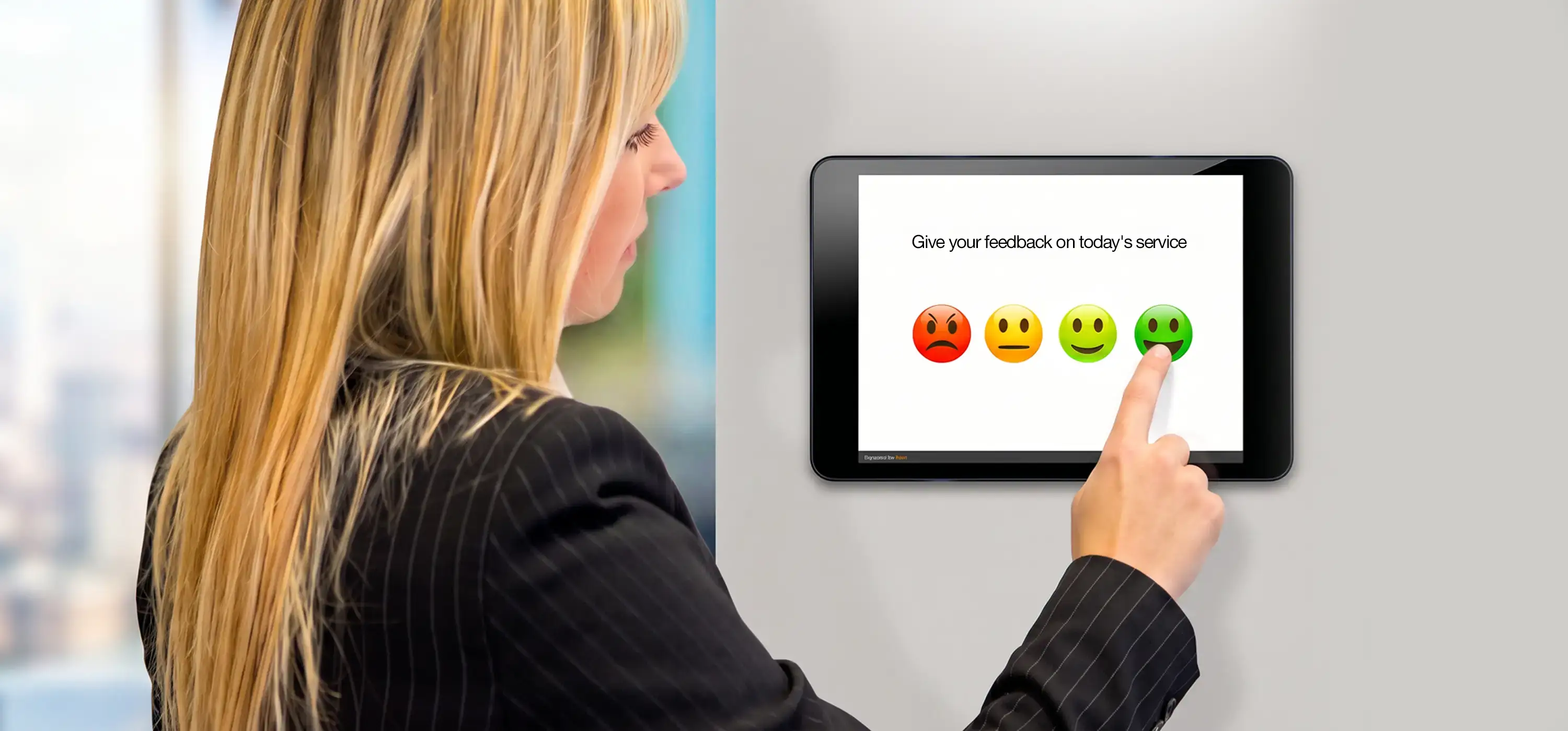 ragazza che risponde ad un sondaggio emoticon o instant survey con tablet a muro